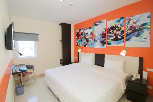 a bedroom with an orange wall with a white bed at Sinar Sport Hotel in Bengkulu