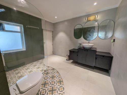 a bathroom with a toilet and a sink and mirrors at Villa Candolim in Candolim