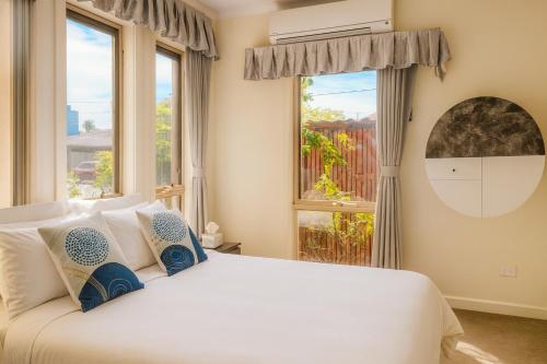 a bedroom with a large white bed with windows at Stylish 4BR Easy CBD Access Walk to Train & Shops in Melbourne
