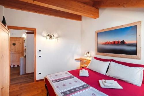 a bedroom with a red bed with a painting on the wall at Dimora La Rocca in Daiano