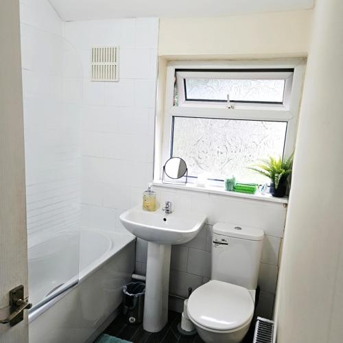 a bathroom with a toilet and a sink and a window at Comfortable 3 bed house in Manchester