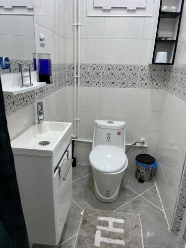 a white bathroom with a toilet and a sink at Le Petit Olivier in Mostaganem