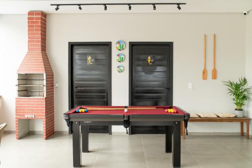 ein Billardtisch in einem Raum mit zwei schwarzen Türen in der Unterkunft Apto com 2 suites a 100m do Japaratinga Resort in São Bento