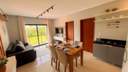 eine Küche und ein Wohnzimmer mit Tisch und Stühlen in der Unterkunft Apto com 2 suites a 100m do Japaratinga Resort in São Bento