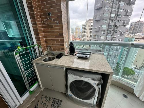 a kitchen with a sink and a balcony with a view at Estanconfor Santos com Vista Mar varanda e garagem in Campo Grande