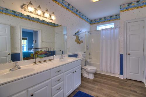 a bathroom with a sink and a toilet and a mirror at Stairway to Havens - South in Myrtle Beach