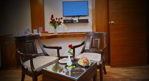 a room with two chairs and a table with a tv at Hotel Seven Hills Tower in Agra