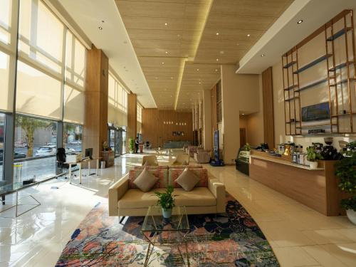 a lobby with a couch and tables in a building at Casa Diora Hotel Al Rawdah in Jeddah