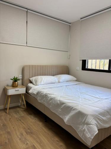 a bedroom with a bed with white sheets and a window at Vila Lidar in Eilat