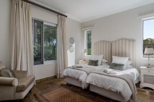 a white bedroom with two beds and a chair at Bonne Chance Luxury Estate in Lynedoch