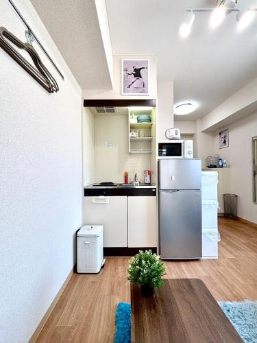 a small kitchen with a refrigerator and a table at 駅徒歩4分 新宿駅7分 バンクシーアートのスタイリッシュルーム in Tokyo