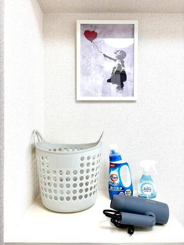 a shelf with a basket and a bottle of soap at 駅徒歩4分 新宿駅7分 バンクシーアートのスタイリッシュルーム in Tokyo