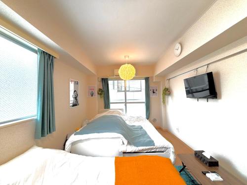 a room with a bed and a tv and a window at 駅徒歩4分 新宿駅7分 バンクシーアートのスタイリッシュルーム in Tokyo