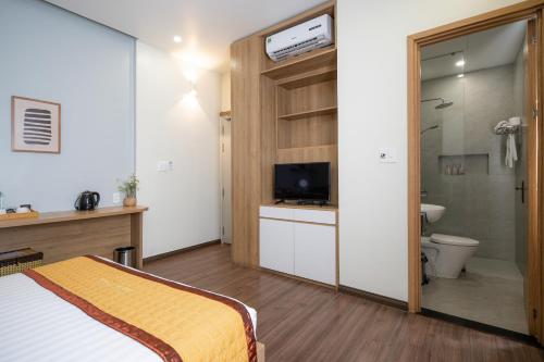 a bedroom with a bed and a toilet and a television at Sline Hotel in Hue