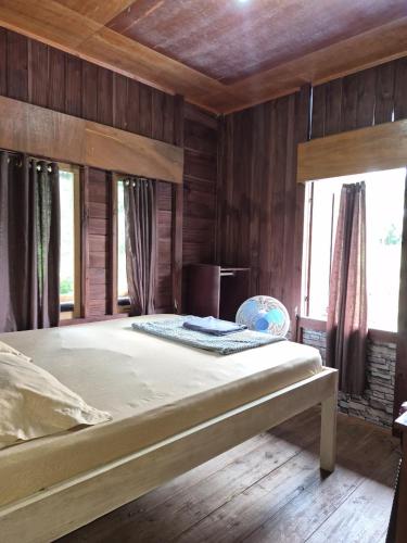 a large bed in a room with wooden walls at Talaga Tomohon Home Stay and Fishing Pond in Tomohon