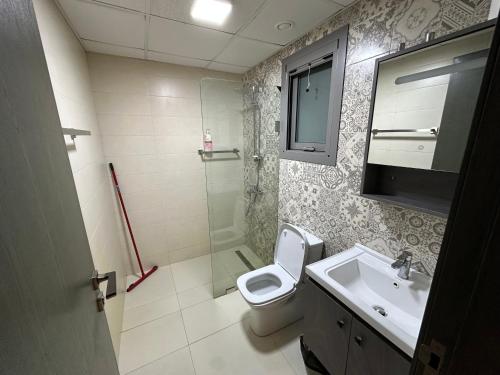 a bathroom with a toilet and a sink and a shower at Pinnacle Row Seaview Elegance in Muscat