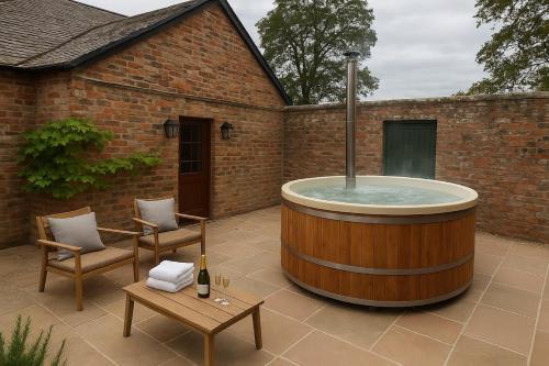 a hot tub in the backyard of a brick building at Courtyard House- Luxury Holiday House with floodlit Tennis court - BRAND NEW in Ainderby Steeple