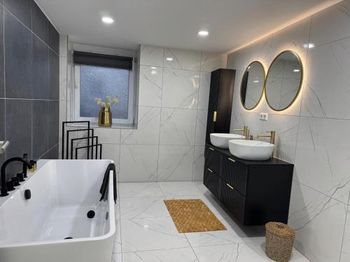 a bathroom with two sinks and a tub and mirrors at M B Homes Lauterstein 10 in Lützelalb