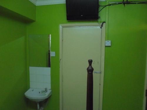 a green bathroom with a sink and a door at New Swanga in Nairobi