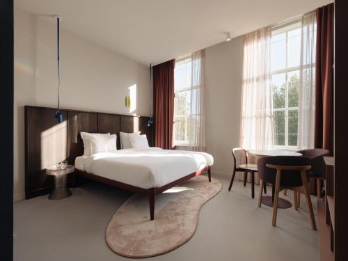 a bedroom with a bed and a table and a desk at Conscious Hotel Oudegracht in Utrecht