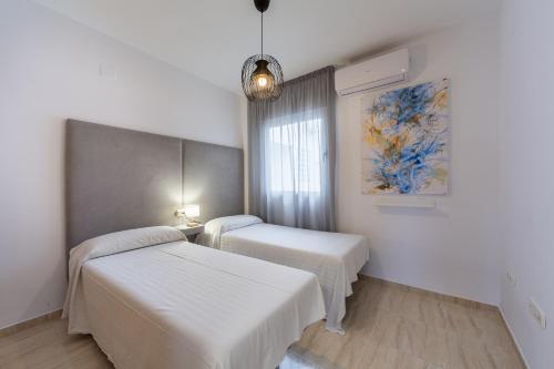 a bedroom with two beds and a painting on the wall at AlmeriaSuite Palm Beach in Almerimar