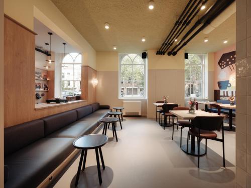a restaurant with a long bench and tables and chairs at Conscious Hotel Oudegracht in Utrecht