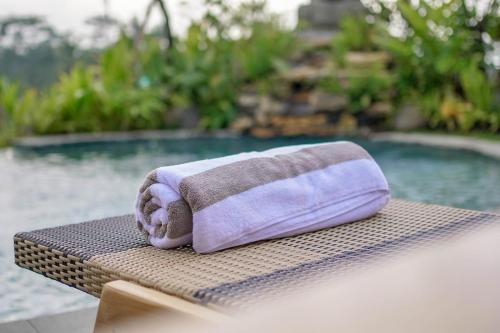 - une serviette assise sur une table à côté d'une piscine dans l'établissement Ningtaru Villa Ubud, à Penginyahan