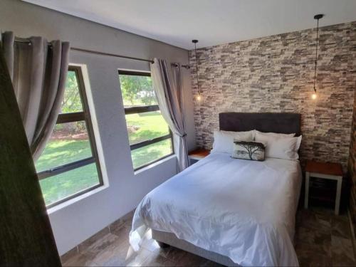Un dormitorio con una cama y dos ventanas. en Villa Rosa Guest Farm, en Eersbewoond