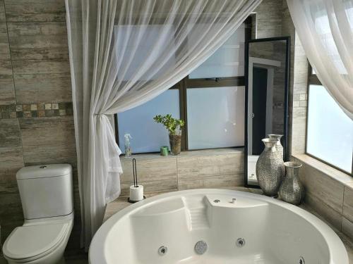 Un baño con bañera, inodoro y ventana. en Villa Rosa Guest Farm, en Eersbewoond