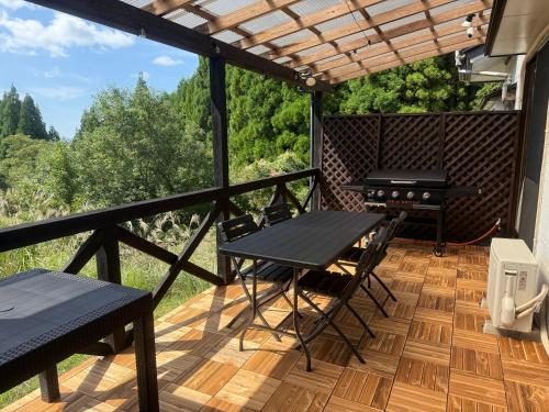 a balcony with a table and chairs and a grill at Echoes of Forest エコーズオブフォレスト 森の音が聴こえるロッジ in Minamioguni