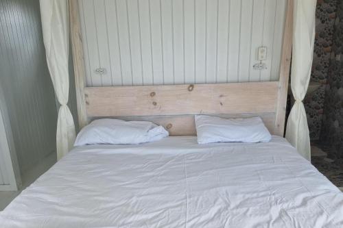 un letto con lenzuola bianche e due cuscini di Captivating 1-Bed Cottage in Codrington a Dulcina