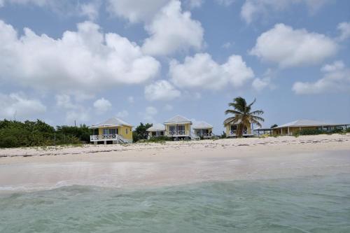 a group of houses on a beach with the water at Captivating 1-Bed Cottage in Codrington in Dulcina