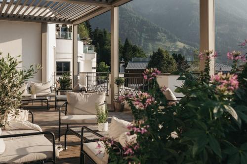 a patio with chairs and flowers on a balcony at Alpina Alpendorf in Sankt Johann im Pongau