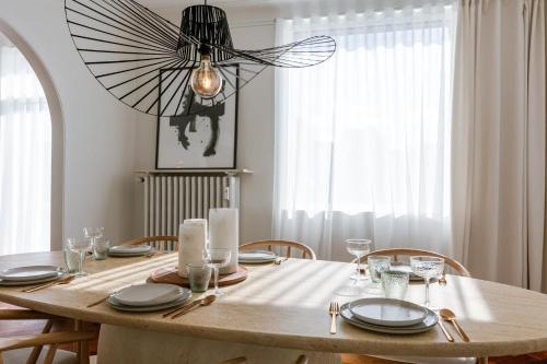 a dining room table with a chandelier hanging over it at Huswell - New Penthouse with City & Harbour Views in Ostend