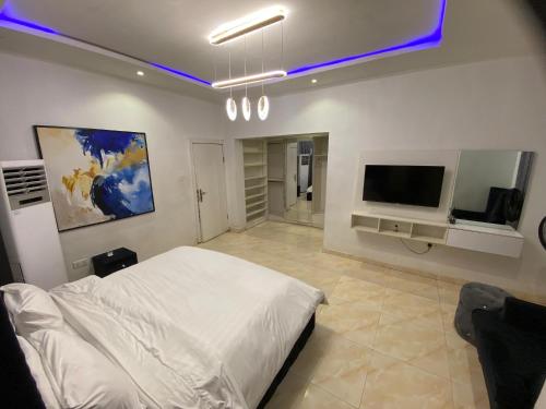 Un dormitorio con una cama blanca y un televisor de pantalla plana. en Residence 22, en Mama