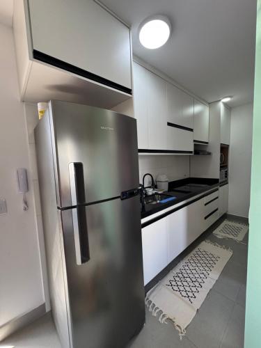 a stainless steel refrigerator in a kitchen with white cabinets at Cobertura Vl Sônia Morumbi in Sao Paulo