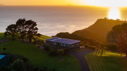 a house on a hill next to the ocean at The Kina Cottage in Tutukaka