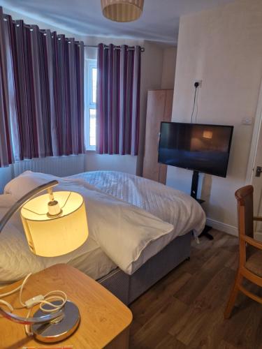 a bedroom with a bed and a flat screen tv at Nest inn luton in Luton