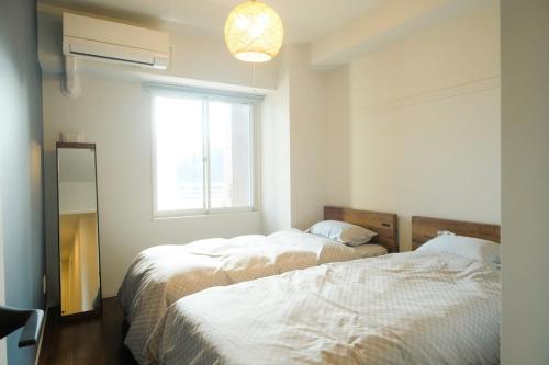 two beds in a room with a window at Stadt Leben東北ゲートウェイI in Sendai