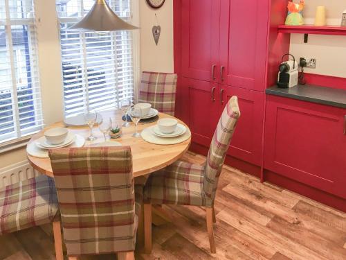 a kitchen with a wooden table with chairs and red cabinets at Upton Down in Keswick
