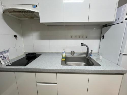 encimera de cocina con fregadero y armarios blancos en Zia, en Seúl