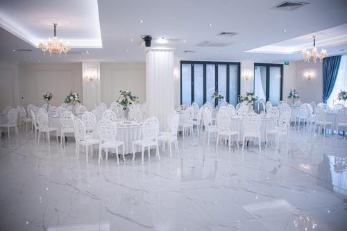 a banquet hall with white tables and chairs and flowers at Hotel Rivera in Dobrich