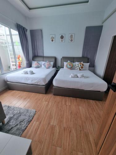 two beds in a room with wooden flooring and a room with two windows at the time pool villa พัทยา in Ban Bung