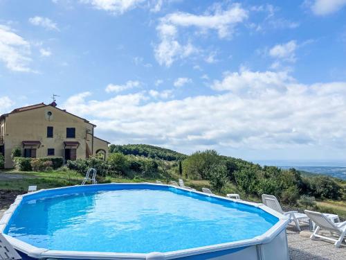 a pool with chairs and a house and the ocean at Apartment Bellavista-1 by Interhome in Castellina Marittima