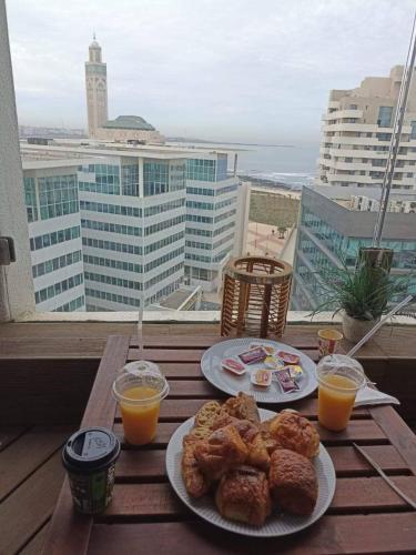 einen Tisch mit zwei Teller Essen und zwei Gläsern Orangensaft in der Unterkunft Stylish Apartment with a seaview 9 in Casablanca