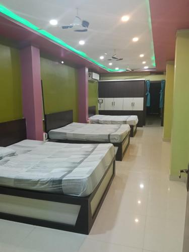 three beds in a room with green and purple at Royal plaza Homestay in Daringbadi