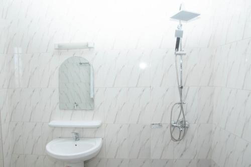 a white bathroom with a sink and a mirror at Yaoundé in Yaoundé