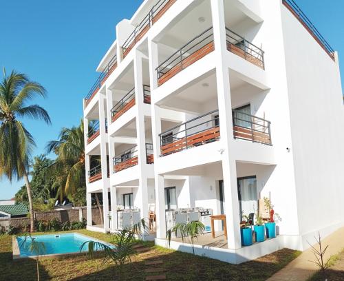 a white apartment building with a swimming pool at Hôtel Fitiavana in Nosy Be