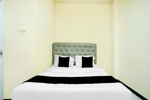 a bed with black and white sheets and pillows at Hotel O Palembang near Palembang City Center Mall formerly Kostel 97 in Palembang