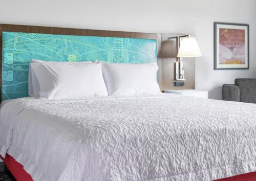 マニトワックにあるHampton Inn Manitowocのベッドルーム(青いヘッドボード付きの白い大型ベッド1台付)
